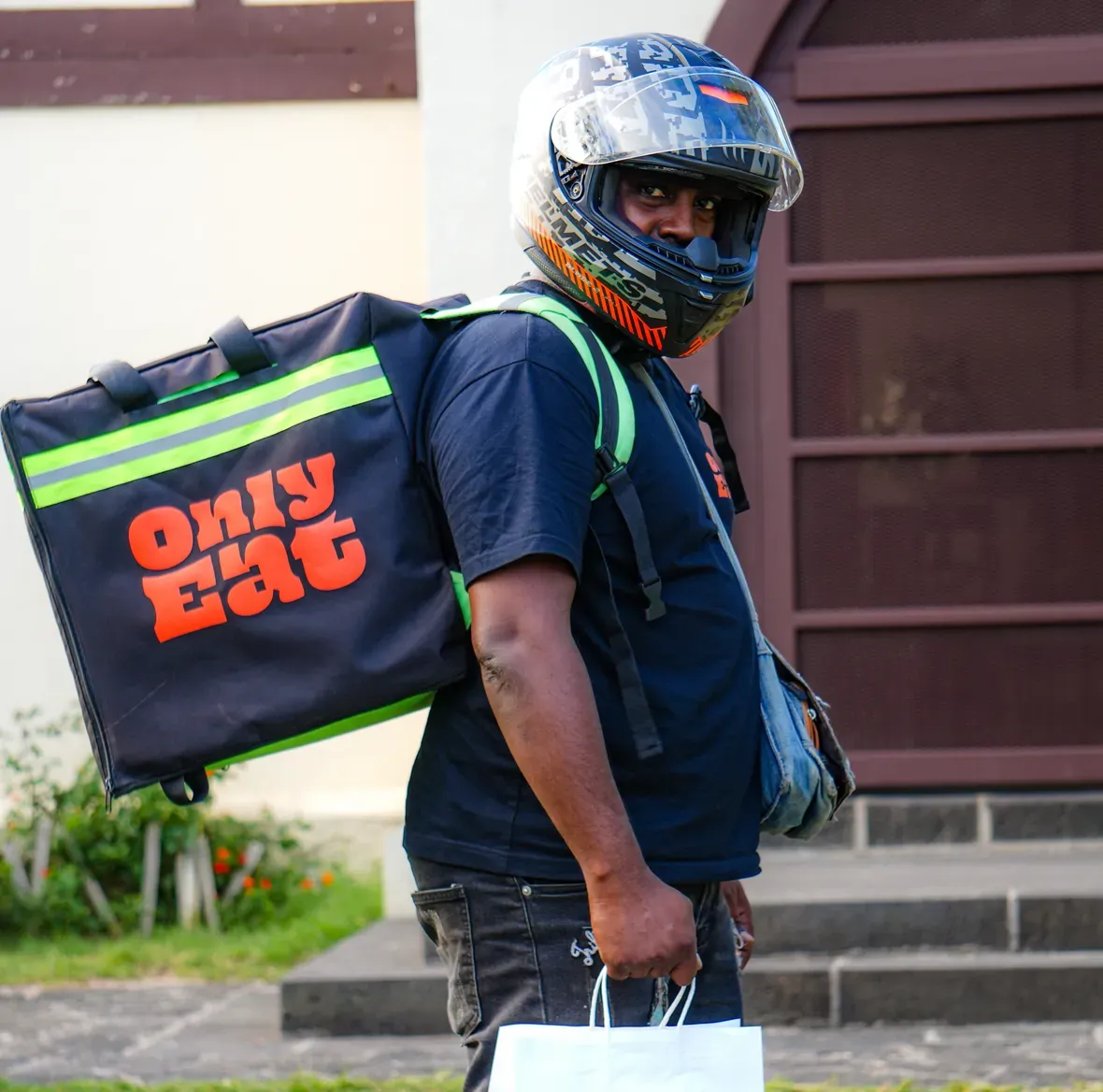 An OnlyEat rider walking up with your takeaway bag, food delivery in Mauritius.
