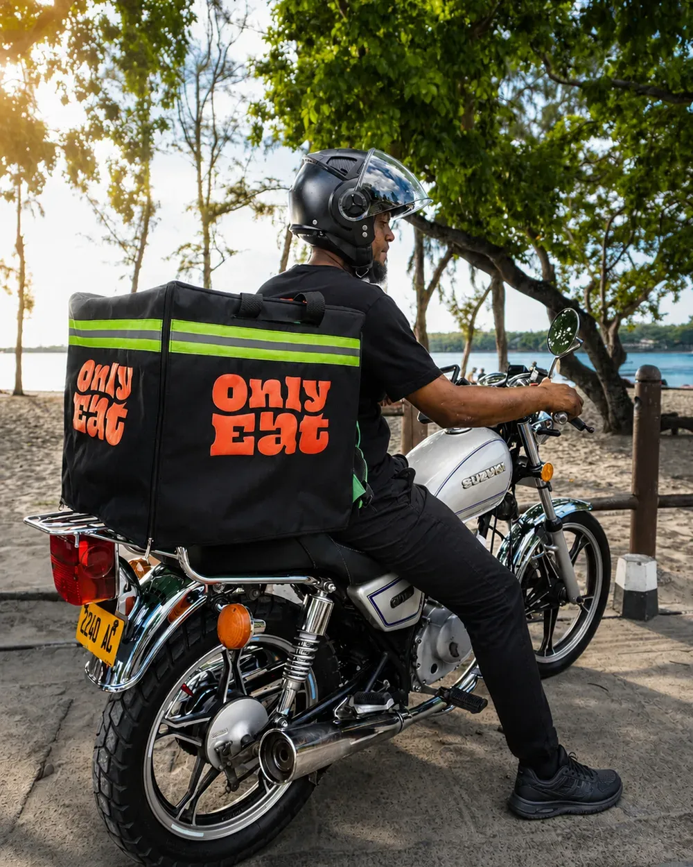 OnlyEat delivery rider on his motorbike with the branded bag, Mauritian beach